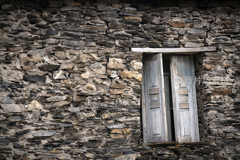 Side Of A Stone House With A Wooden Door and SmClose photo Of A old Stone building的一面。